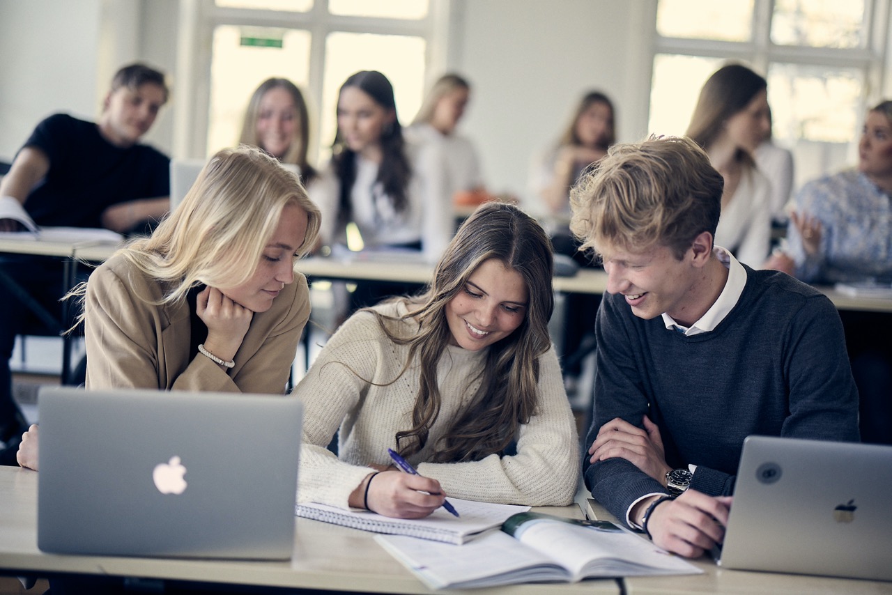 Elever på ProCivitas under en lektion. 3 elever sitter tillsammans och studerar.