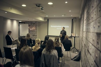 En elev står och presenterar sitt gymnasiearbete framför en publik.