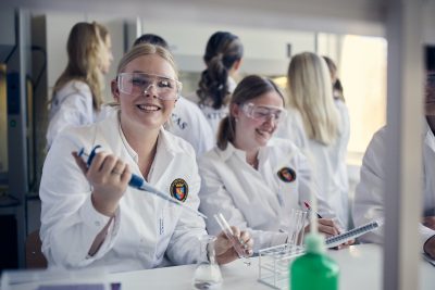 Elever med vita rockar och skyddsglasögon