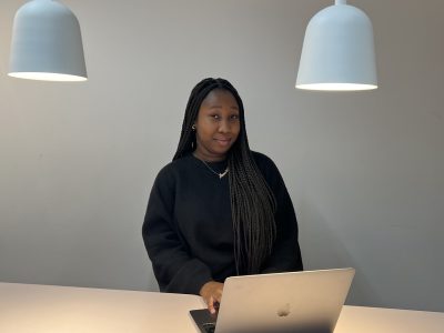 Amie sitter vid ett bord med sin dator och studerar