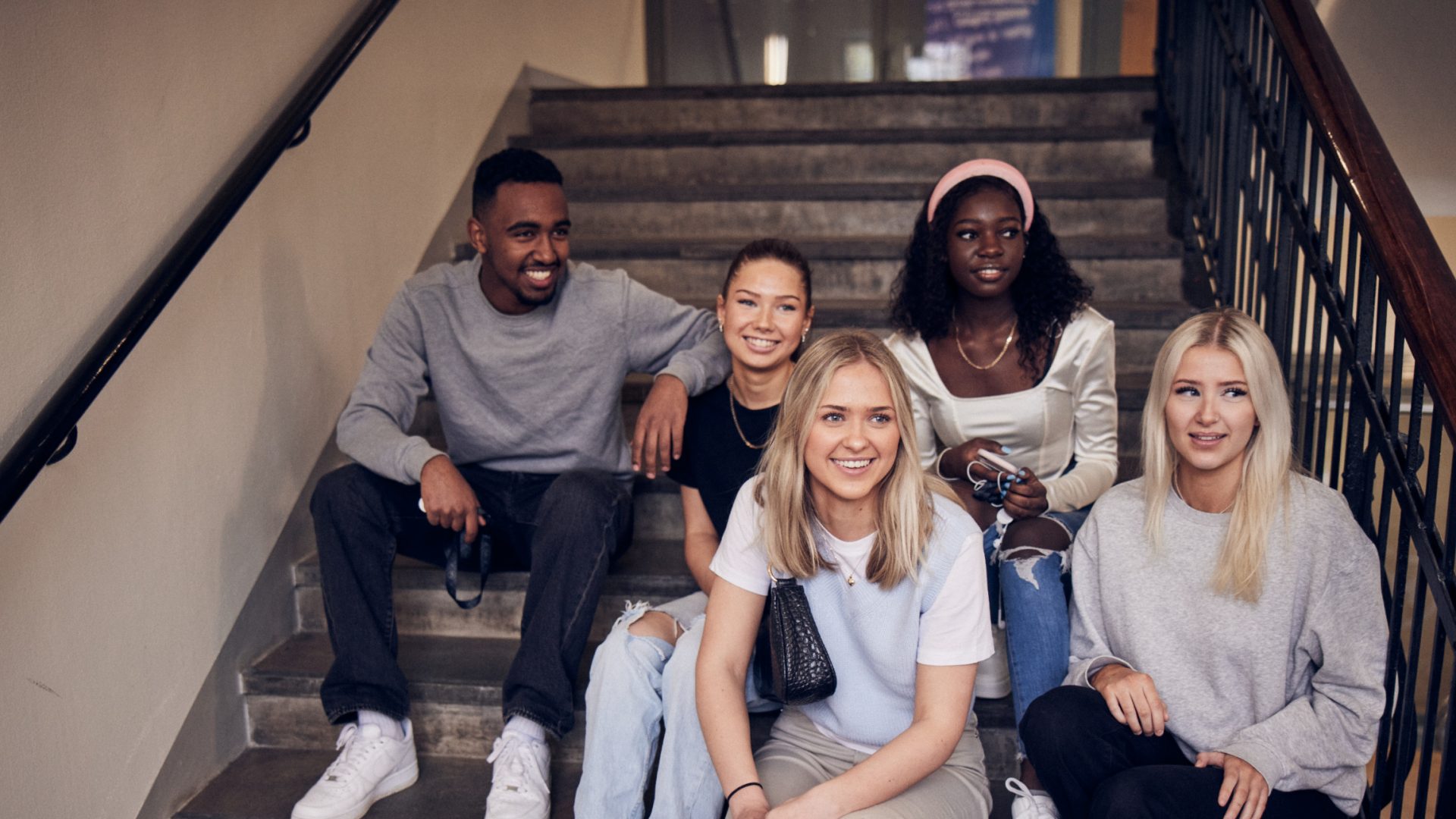 Elever på ProCivitas sitter i en trappa i skolan.