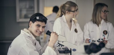 Glad elev tittar i mikroskop.