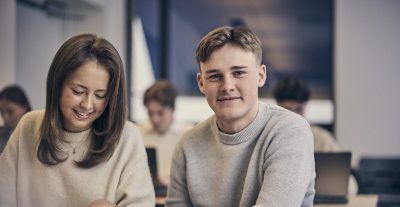 Elev tittar rakt in i kameran och ler.