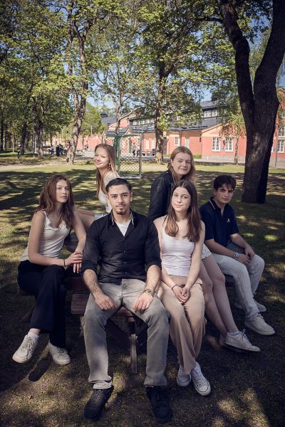 En grupp elever poserar tillsammans utomhus på en solig dag.