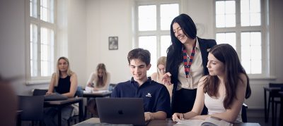 Två studenter som samarbetar medan en av dem skrattar glatt.