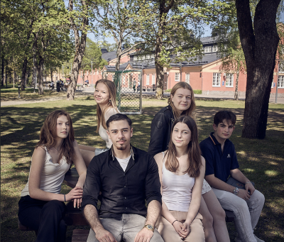 En grupp elever poserar tillsammans utomhus på en bänk.