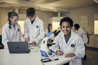 Elev ler och tittar rakt in i kameran under naturlektion.