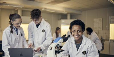 Elev ler och tittar rakt in i kameran under naturlektion.